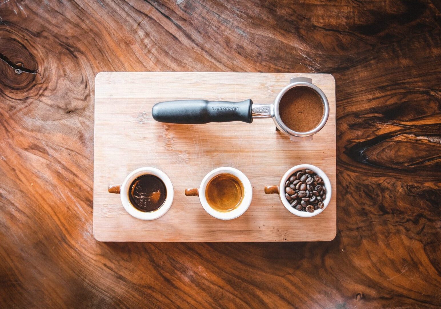 A wooden board with four cups of coffee on it.